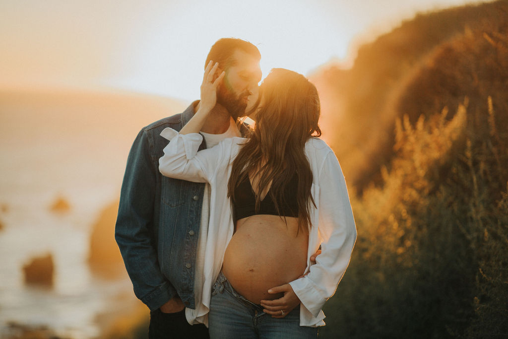 Couple kissing - maternity photo with sunset at a beach